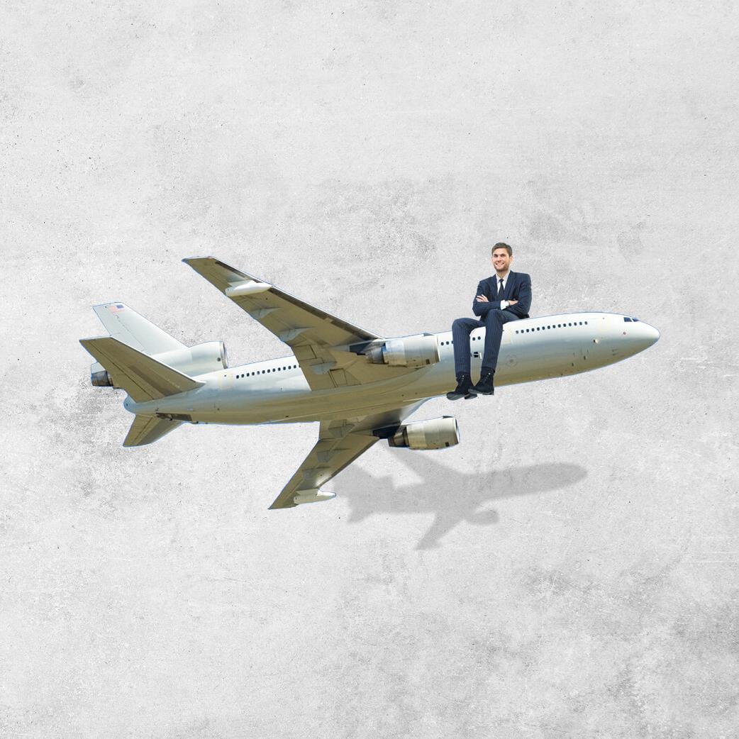 一个西装革履的男人坐在一架小型商用飞机的机头上